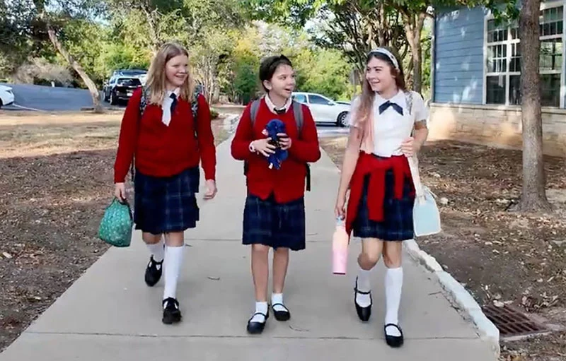 Three girls walking into The Texas Girls School wearing their school uniforms.