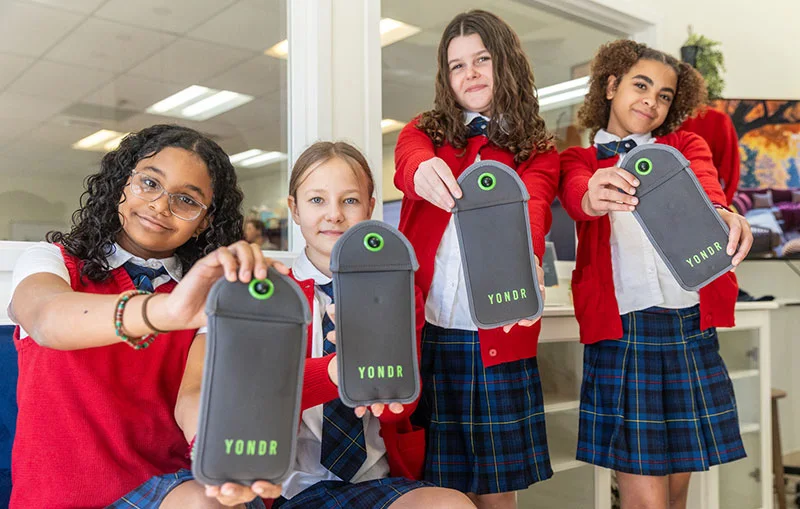 4 students holding yonder bags and smiling