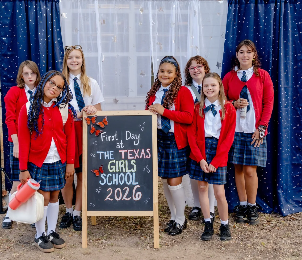 Seven students pose together beside the "First Day of The Texas Girls School 2026" sign.