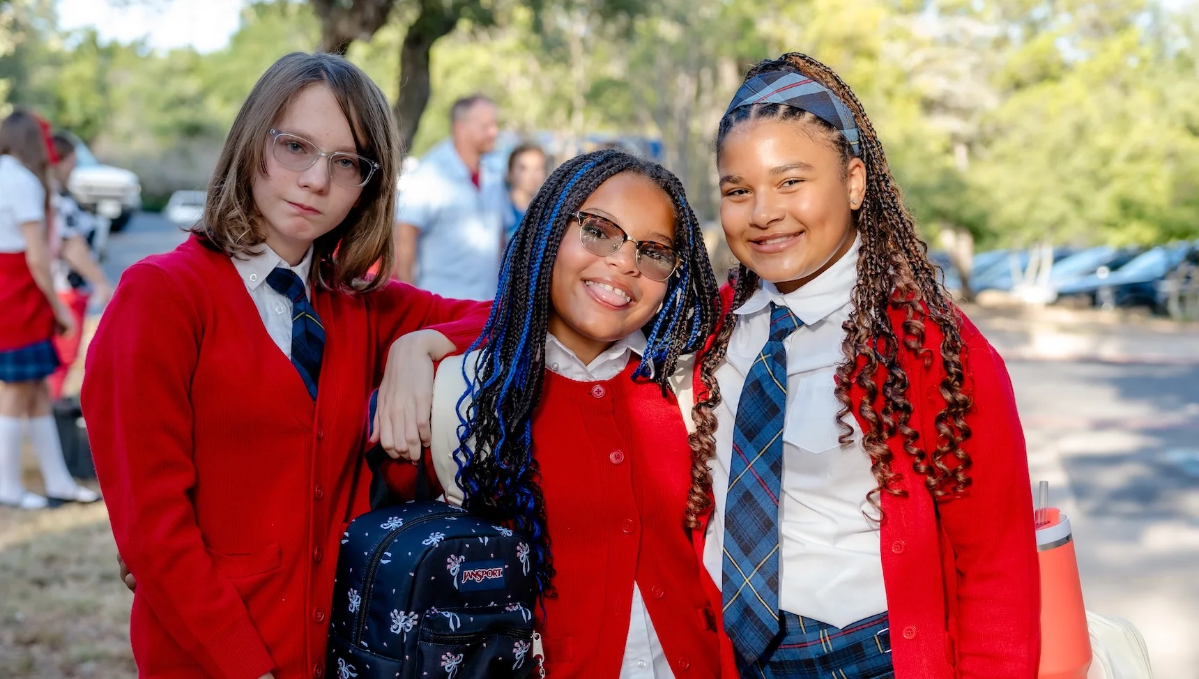 Avery-friend-hor Three middle school girls in red cardigans smile together outdoors at The Texas Girls School in Austin, TX