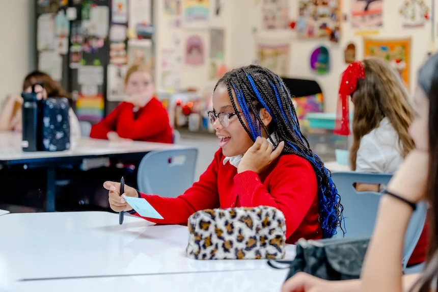 A student with braided hair reads and writes at her desk in a classroom at the tuition-free Texas Girls School.