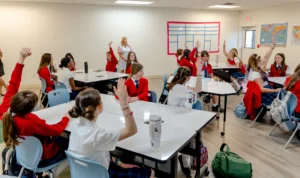 classroom-1720×1022-hor Students in red cardigans work at their desks in a Texas Girls School classroom.