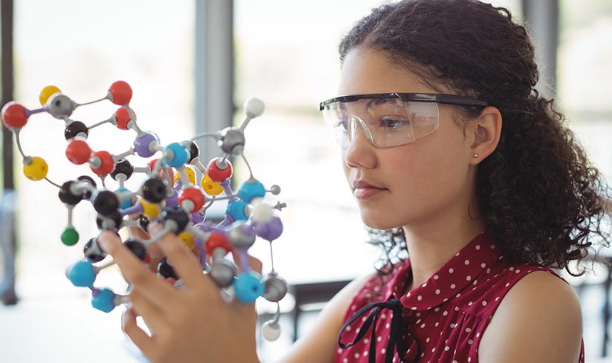 column-header-3 girl holding a 3-d molecule structure in class. she is wearing safety glasses