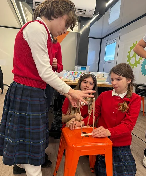girls in red cardigans at laptops in classroom