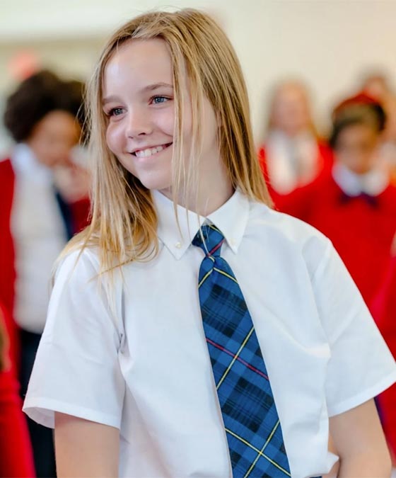 smiling blonde girl wearing white shirt and blue tie