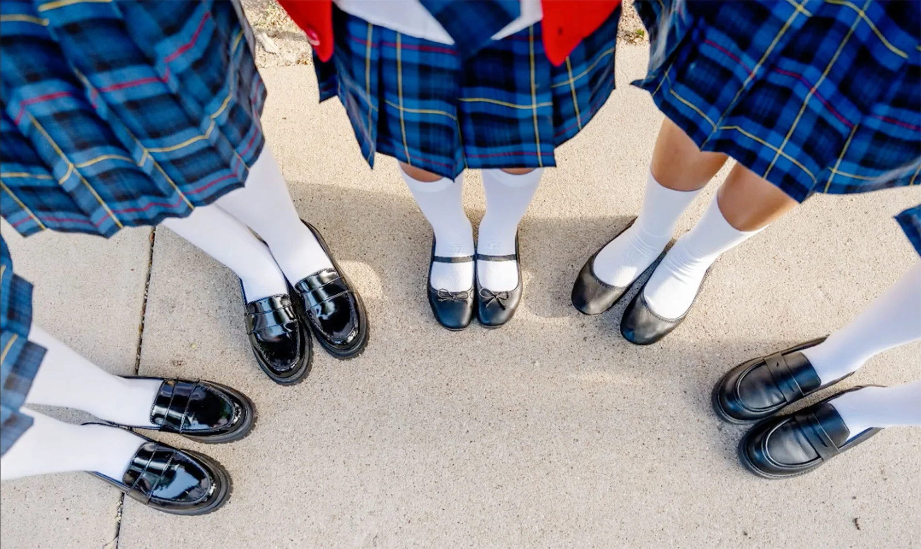 View of girls uniforms and shoes facing down, sunny day