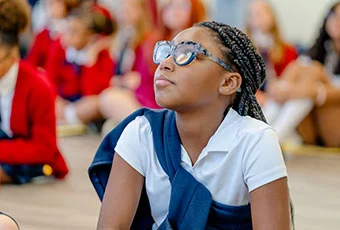 Girl looks up while paying attention to a speaker.