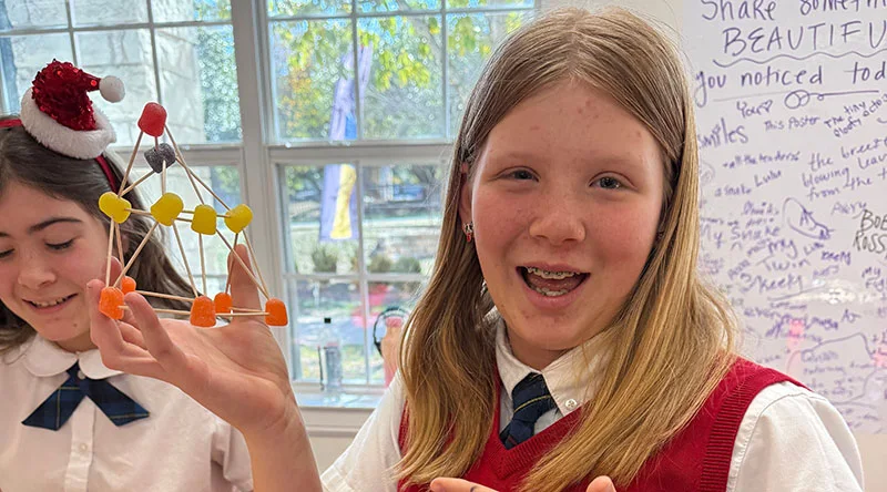 Student holding her project and pointing